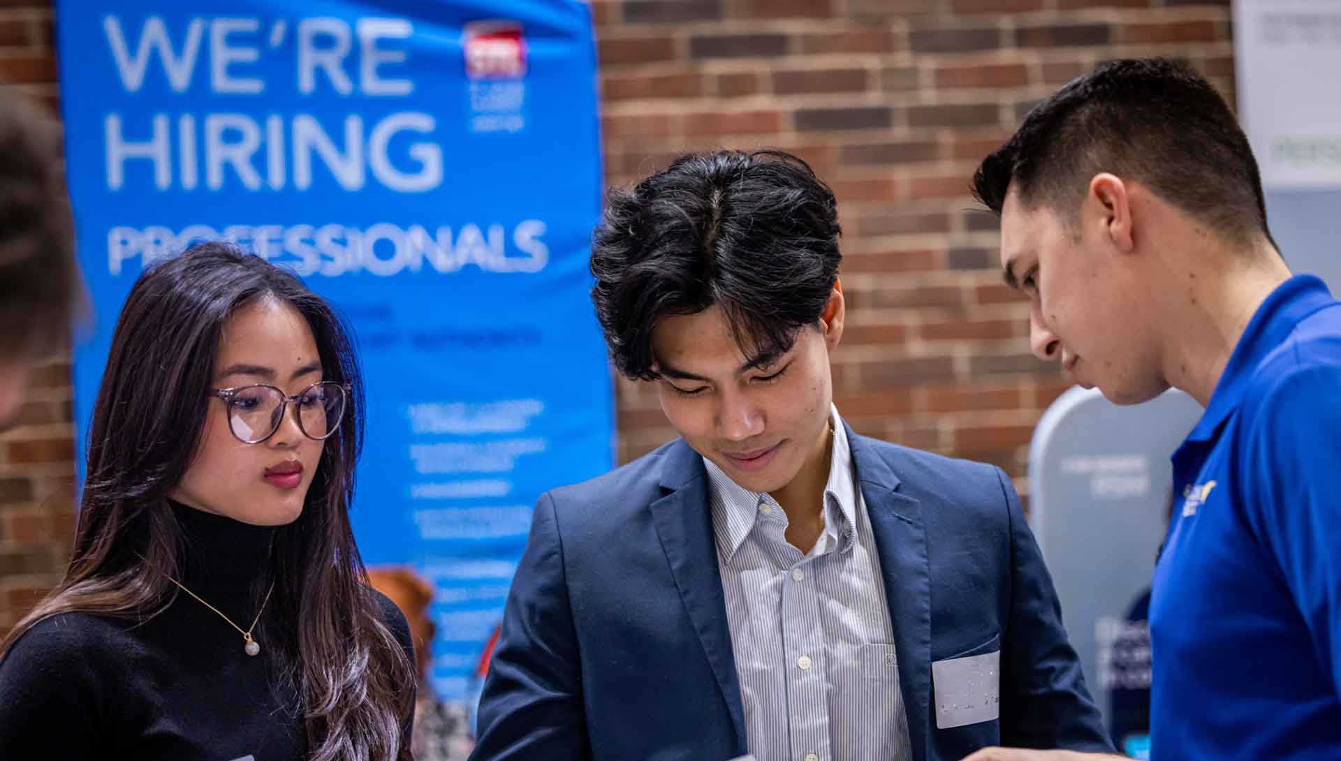 Three students confer at a campus career fair