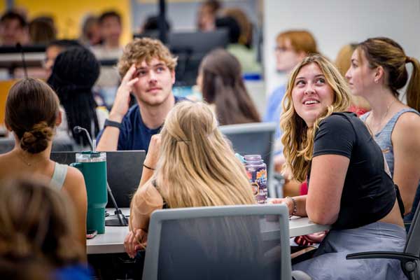 A group of students sits around a table in class settting