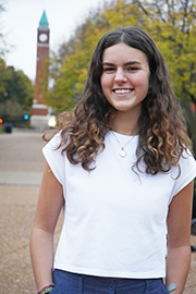 A headshot photo of Anna Godlewski with a clocktower and trees in the background.