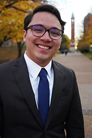 A headshot photo of Nate Reyes with a clocktower and trees in the background.