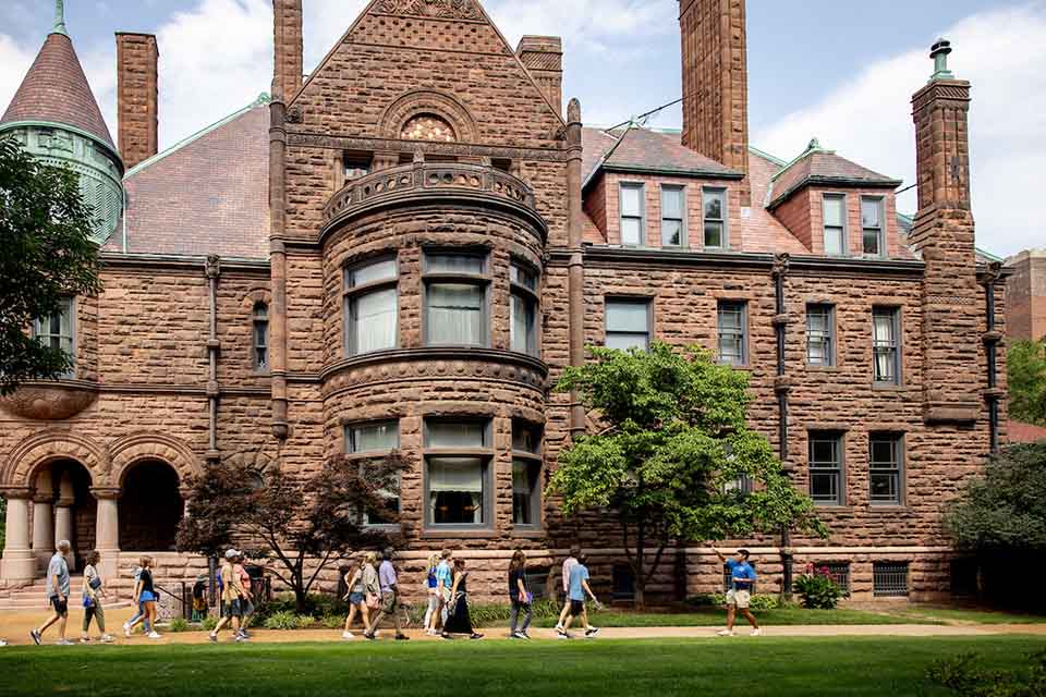 A tour of prospective students passes in front of Cupples House on a sunny day