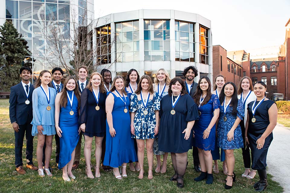 A large group of students pose for a photo outside on campus.