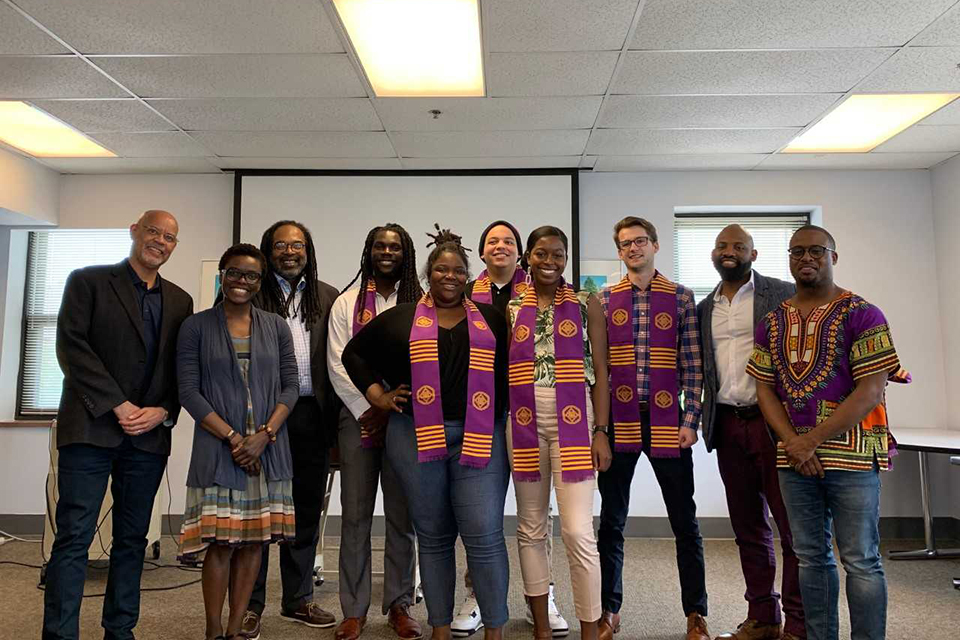 Members of the African American Studies department smile while standing at the front of a classroom.