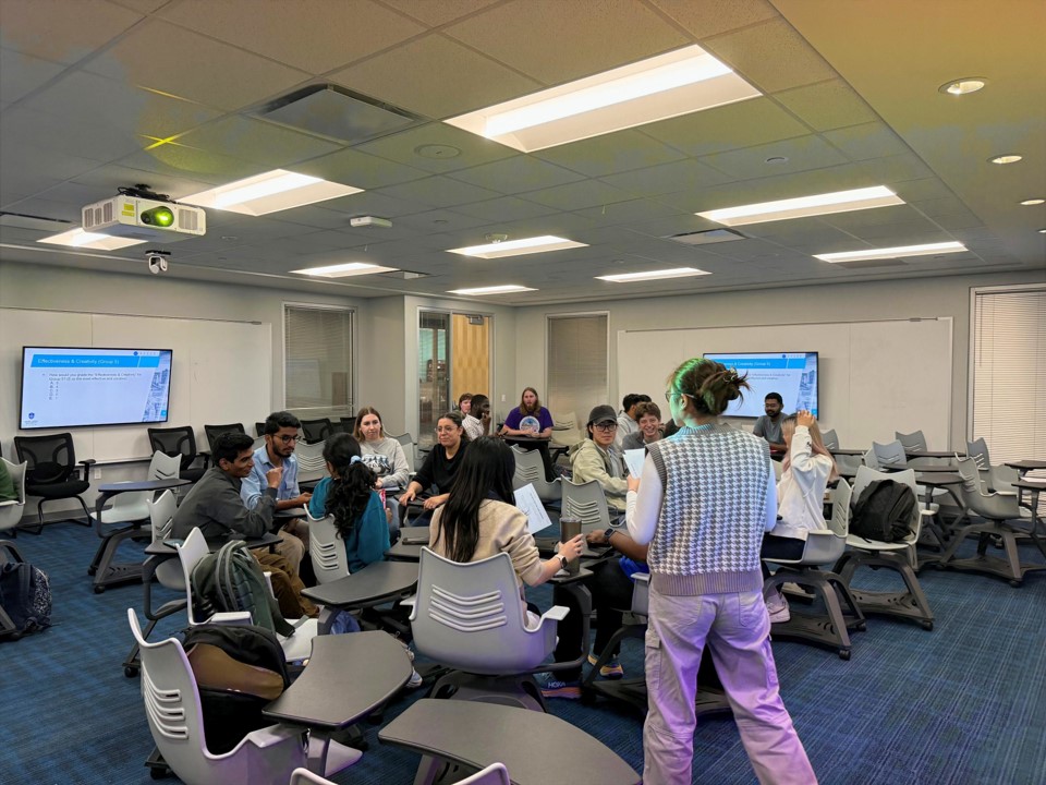 Biology Students at SLU Students sit at desks in a genomics class while one stands in front of the group.