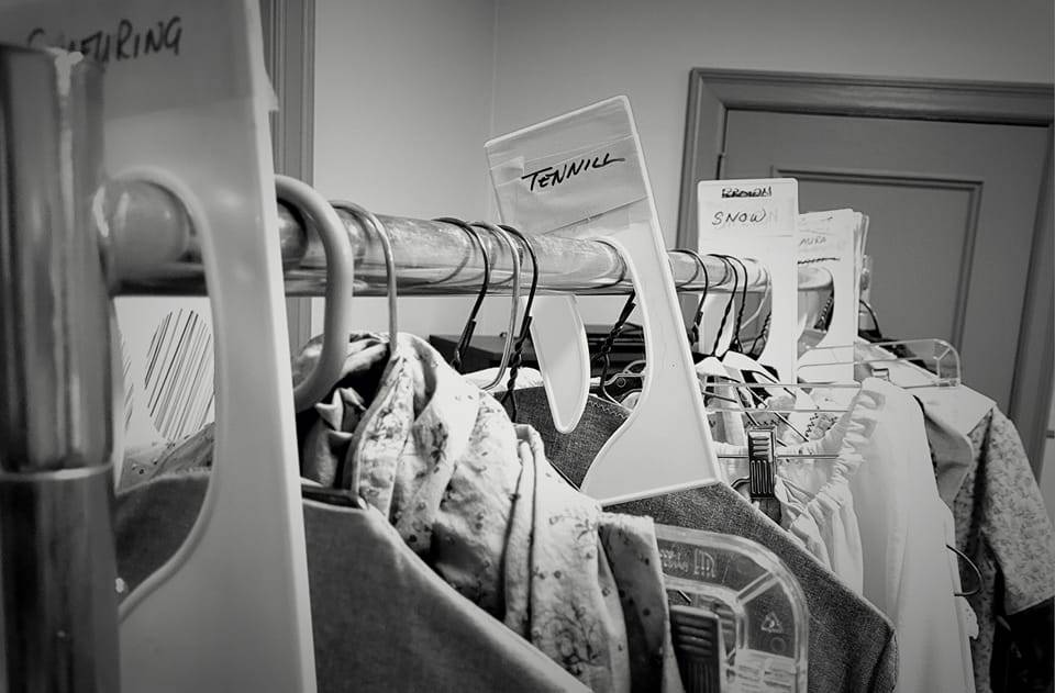 A rack of costumes with a divider labeled "Tennill""