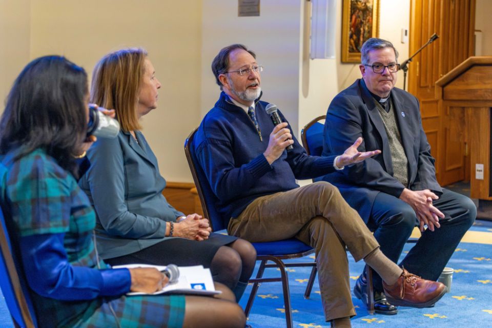 a man sits in the middle of a row of people speaking into a microphone