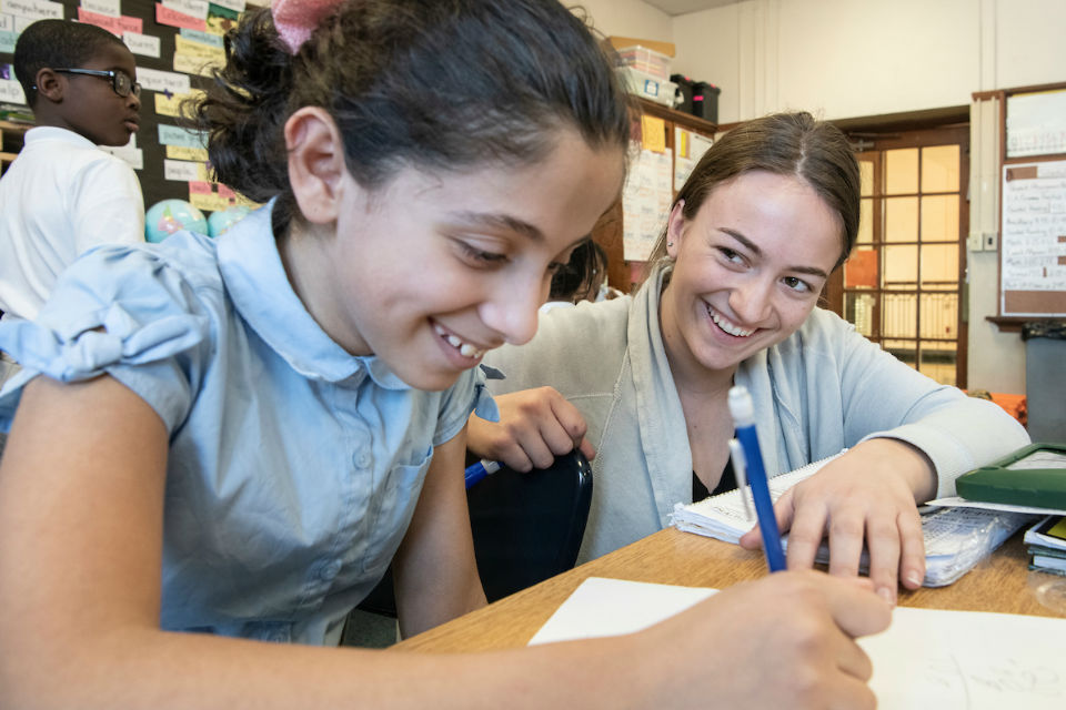 Student and classroom teacher working at a desk.