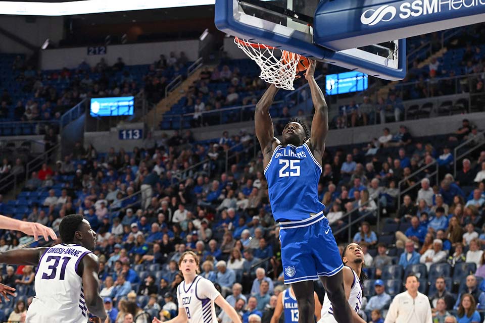 A men's basketball player jumps toward the basket with ball in hand.