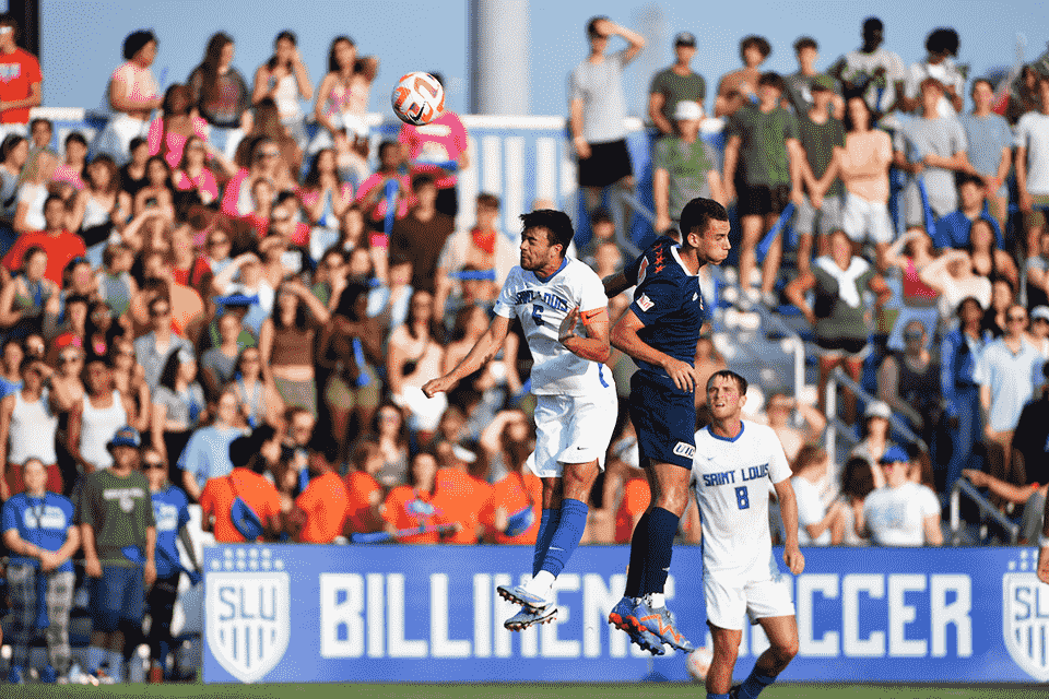 Men's soccer player headbutts the ball away from an opponent.