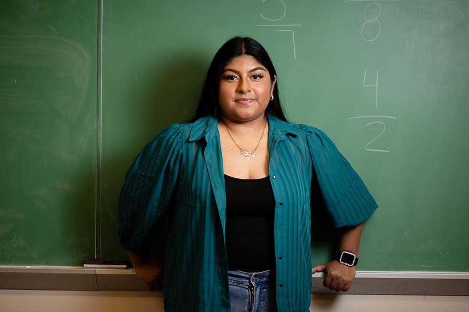 Esme Garcia poses for a photo in front of a chalkboard.