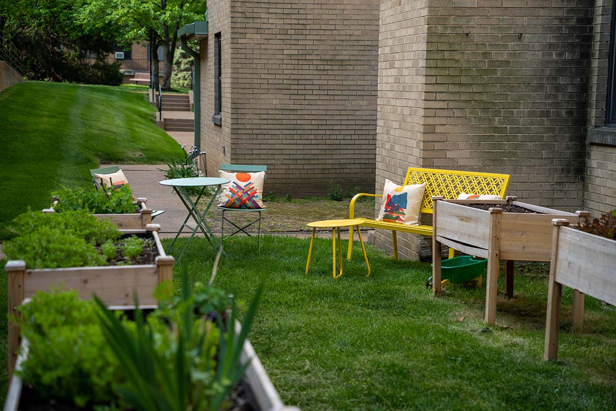 Brightly colored chairs sitting on a lawn outside a building with landscape boxes nearby.