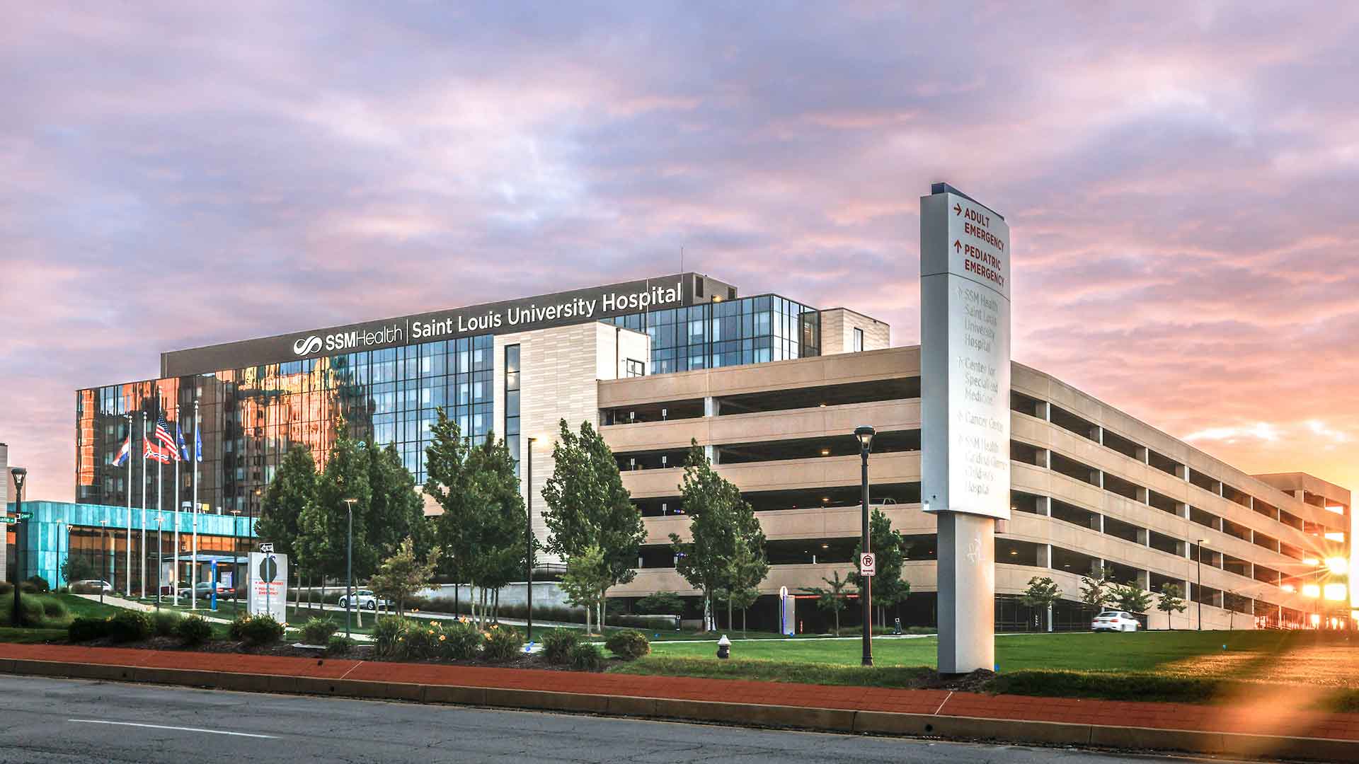 An exterior view of the Saint Louis University Hospital, a large modern building, at sunset.