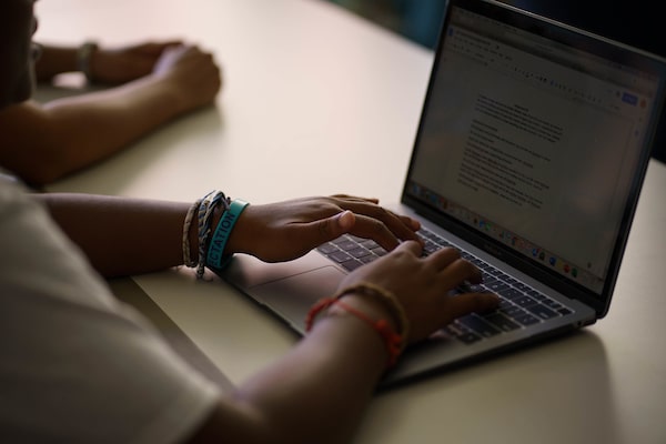 A close up of a student’s hands working on a laptop at a desk.