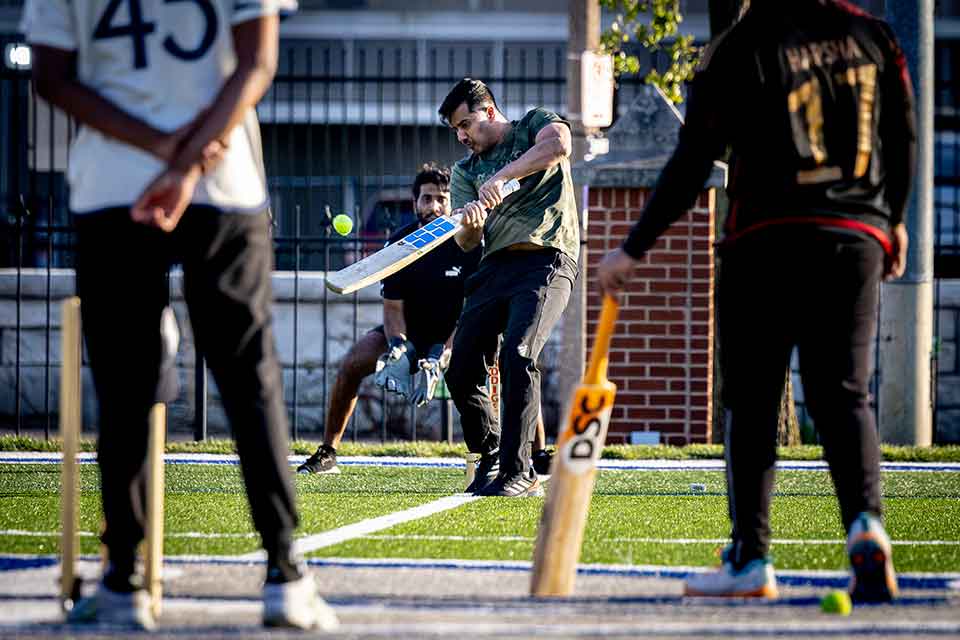 A cricket batter hits the ball during a game on a cricket field.